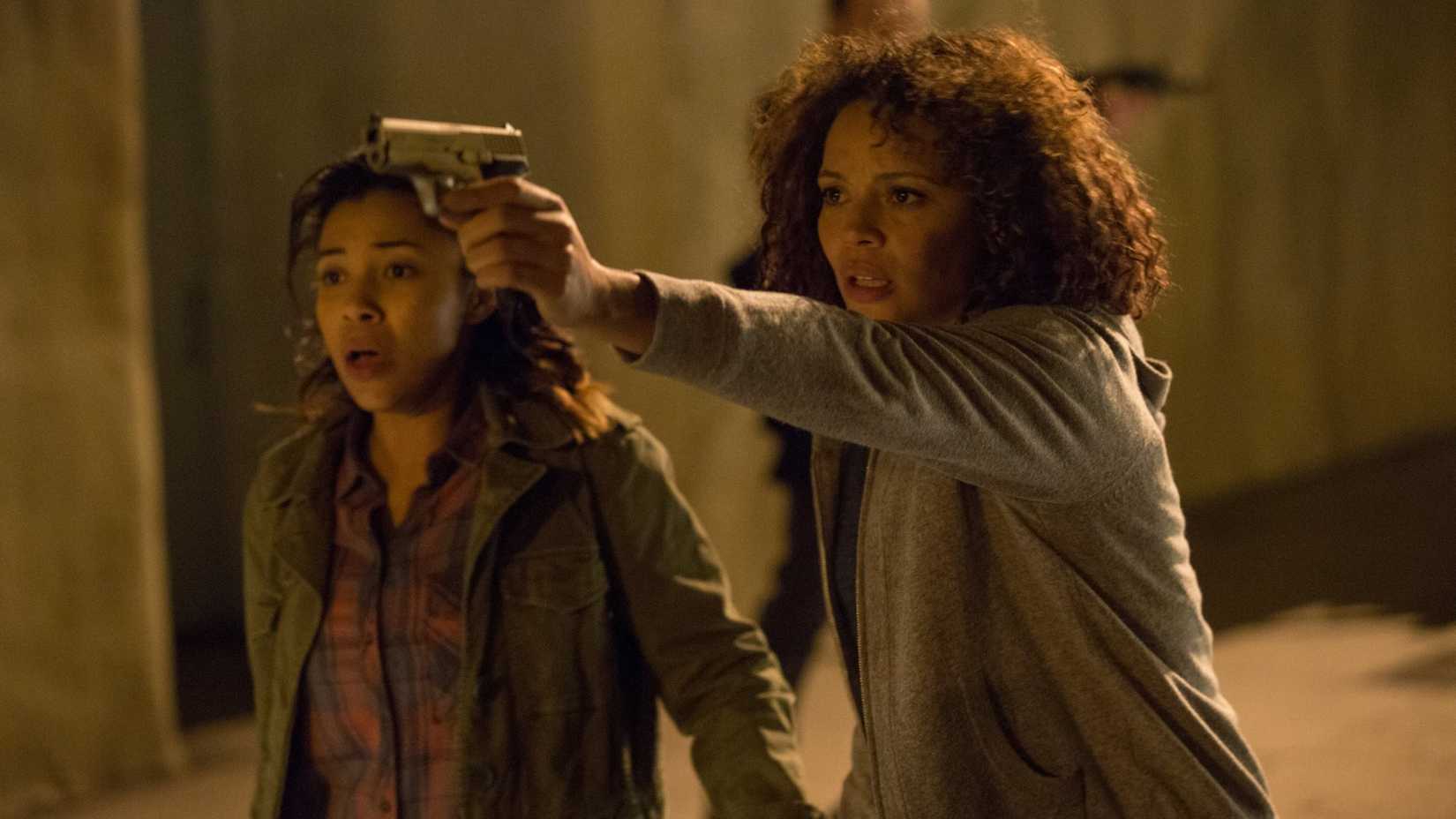 Uma mulher aponta uma arma para fora da tela em The Purge: Anarchy