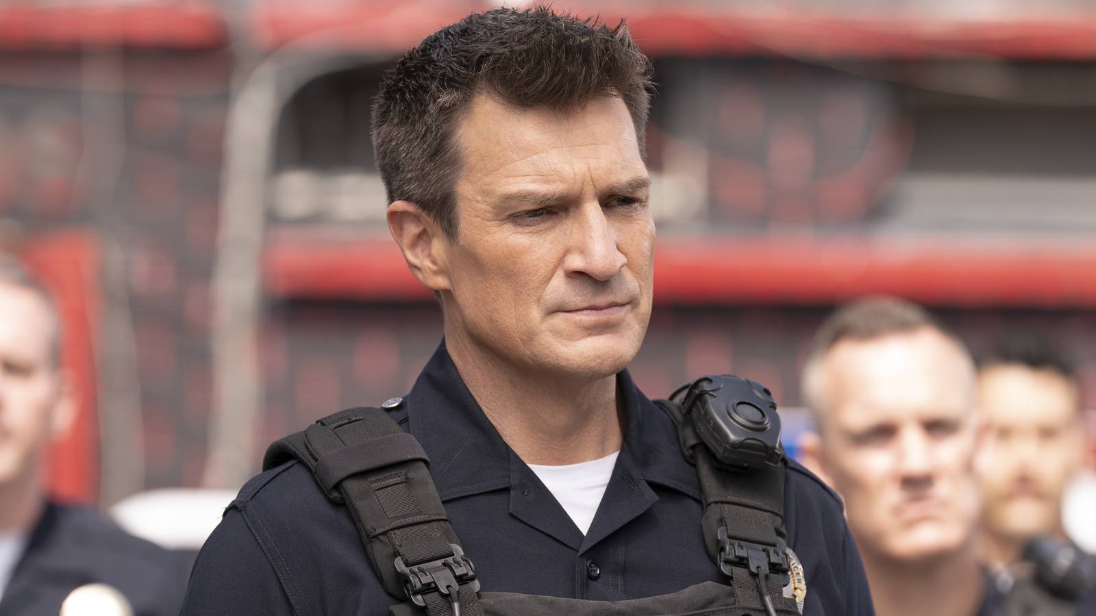 John Nolan (Nathan Fillion) in uniform and surrounded by other cops in The Rookie