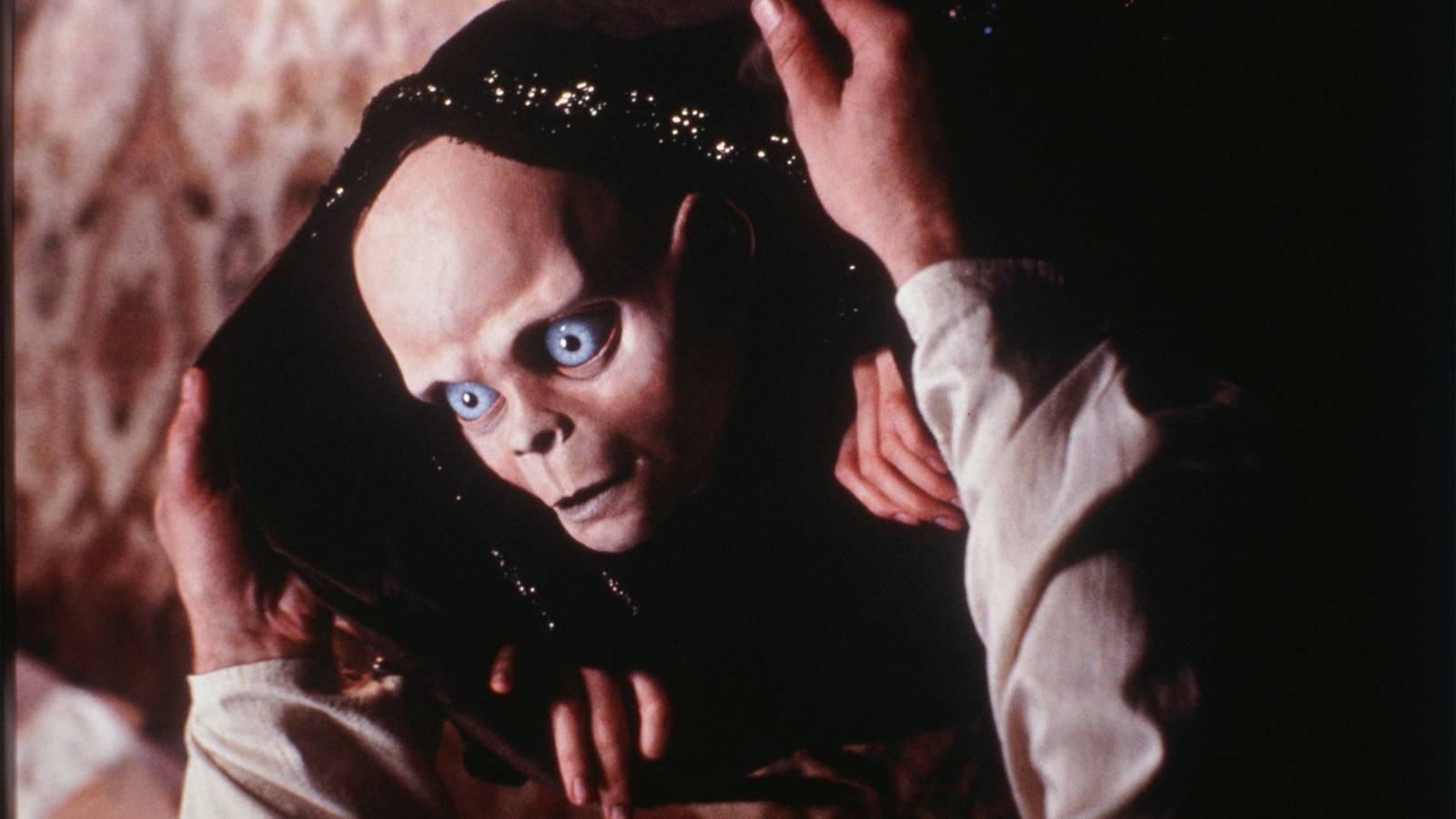 A small goblin-like puppet creature peering out of a hood in The Storyteller.