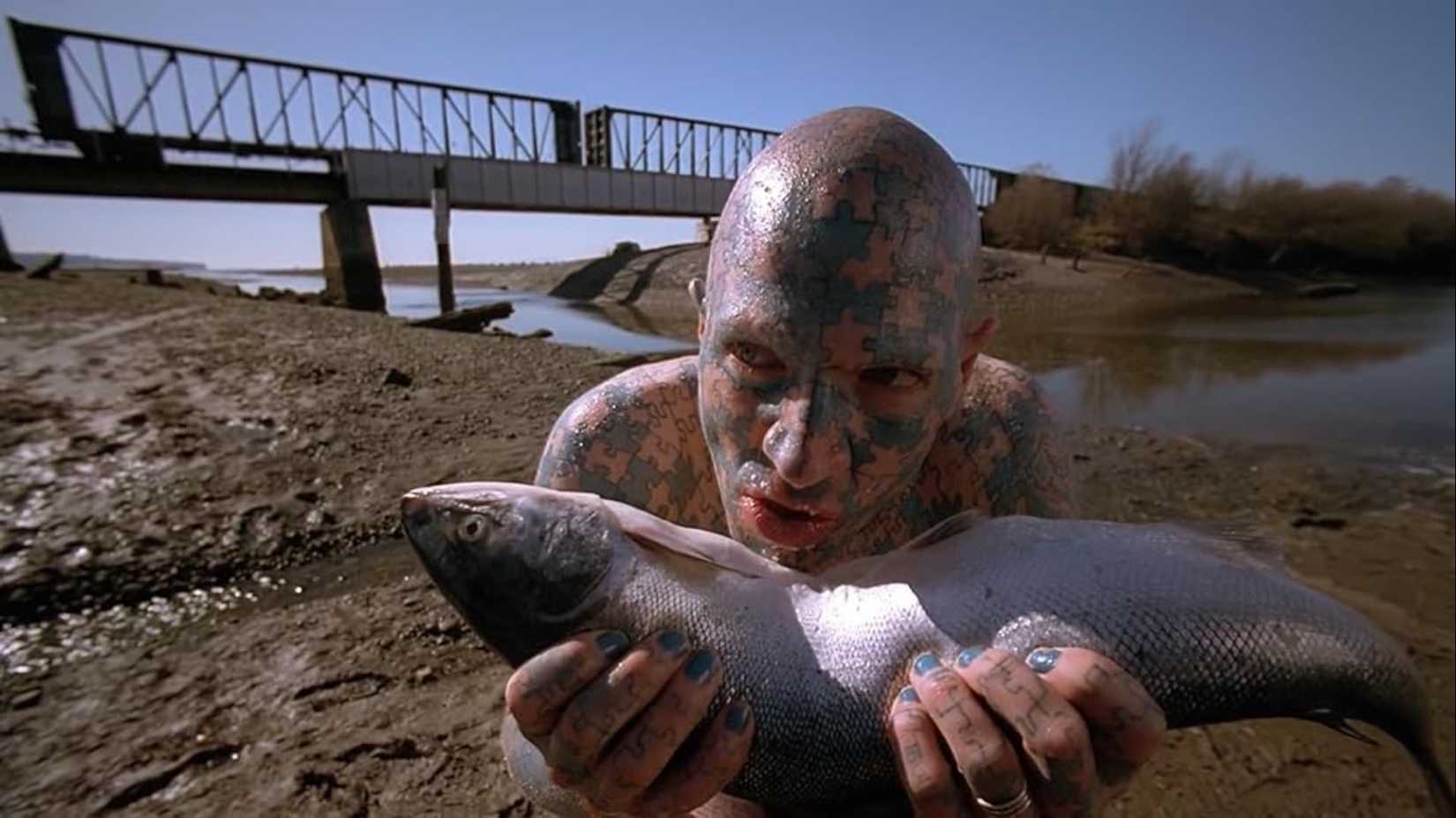 Um homem comendo um peixe cru no episódio "Humbug" de The X-Files.