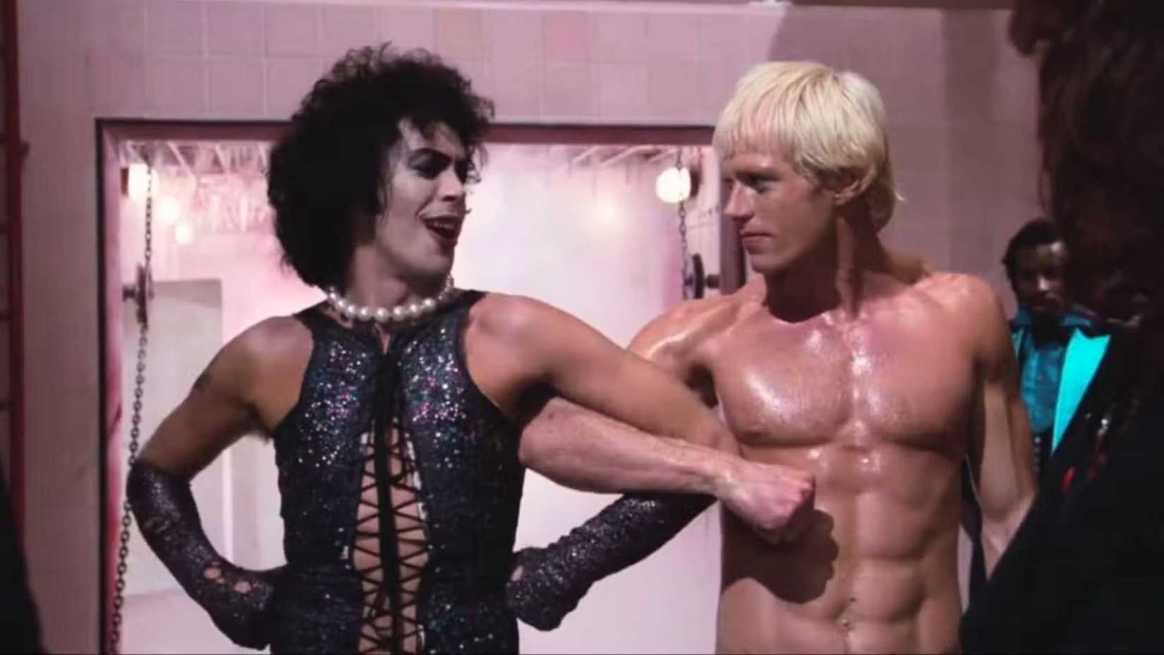 Tim Curry como Frank-N-Furter de braços dados com Peter Hinwood como Rocky em The Rocky Horror Picture Show