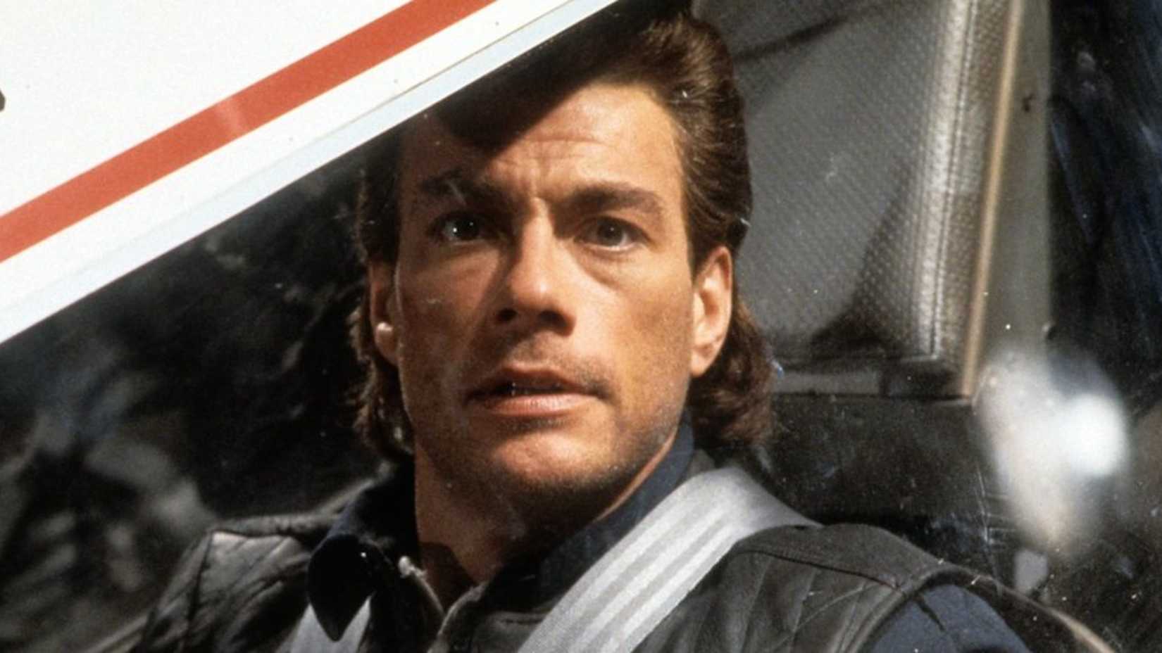 Jean-Claude Van Damme parece sério ao sentar em uma cabine em Timecop: O Guardião do Tempo