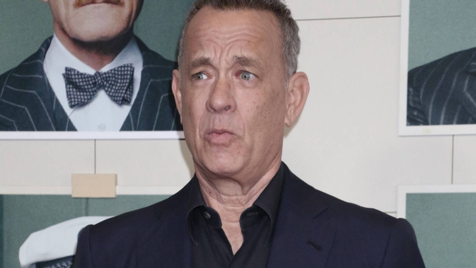 Tom Hanks raising his eyebrows while posing on a red carpet