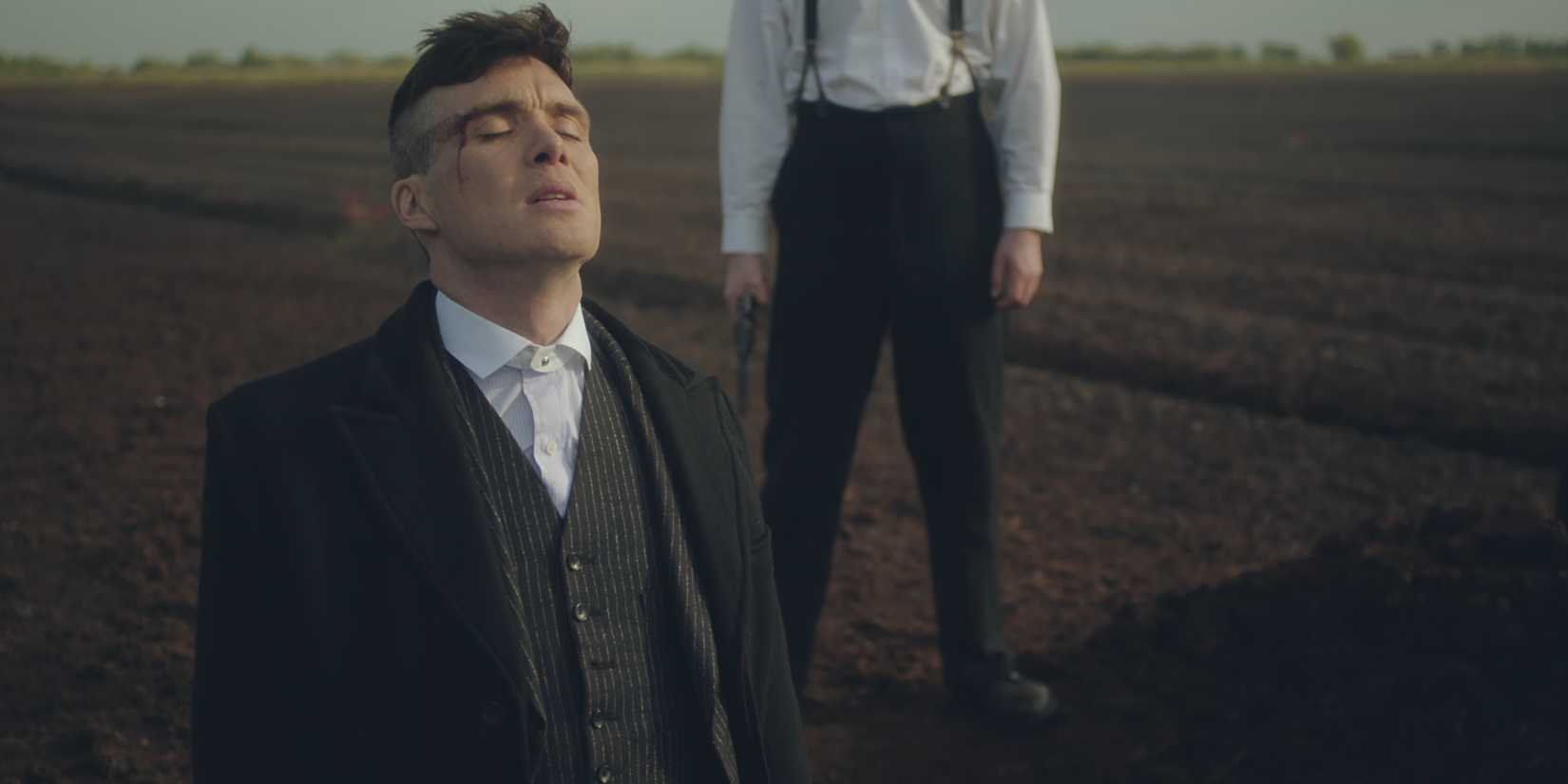 Tommy Shelby (Cillian Murphy) de joelhos com os olhos fechados enquanto um homem com uma arma está atrás dele em Peaky Blinders, temporada 2, episódio 6.