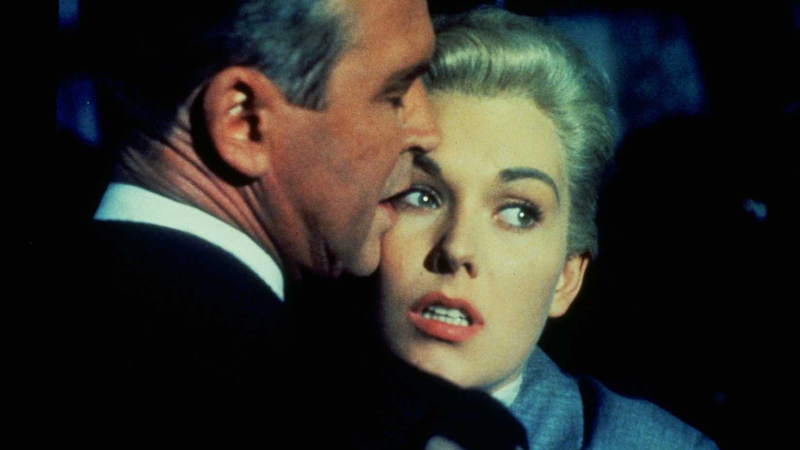 Kim Novak parece assustada enquanto abraça Jimmy Stewart em Um Corpo que Cai