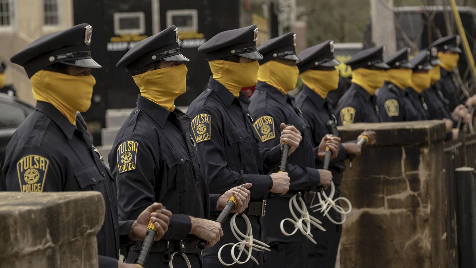 Watchmen cops wearing yellow masks and batons.