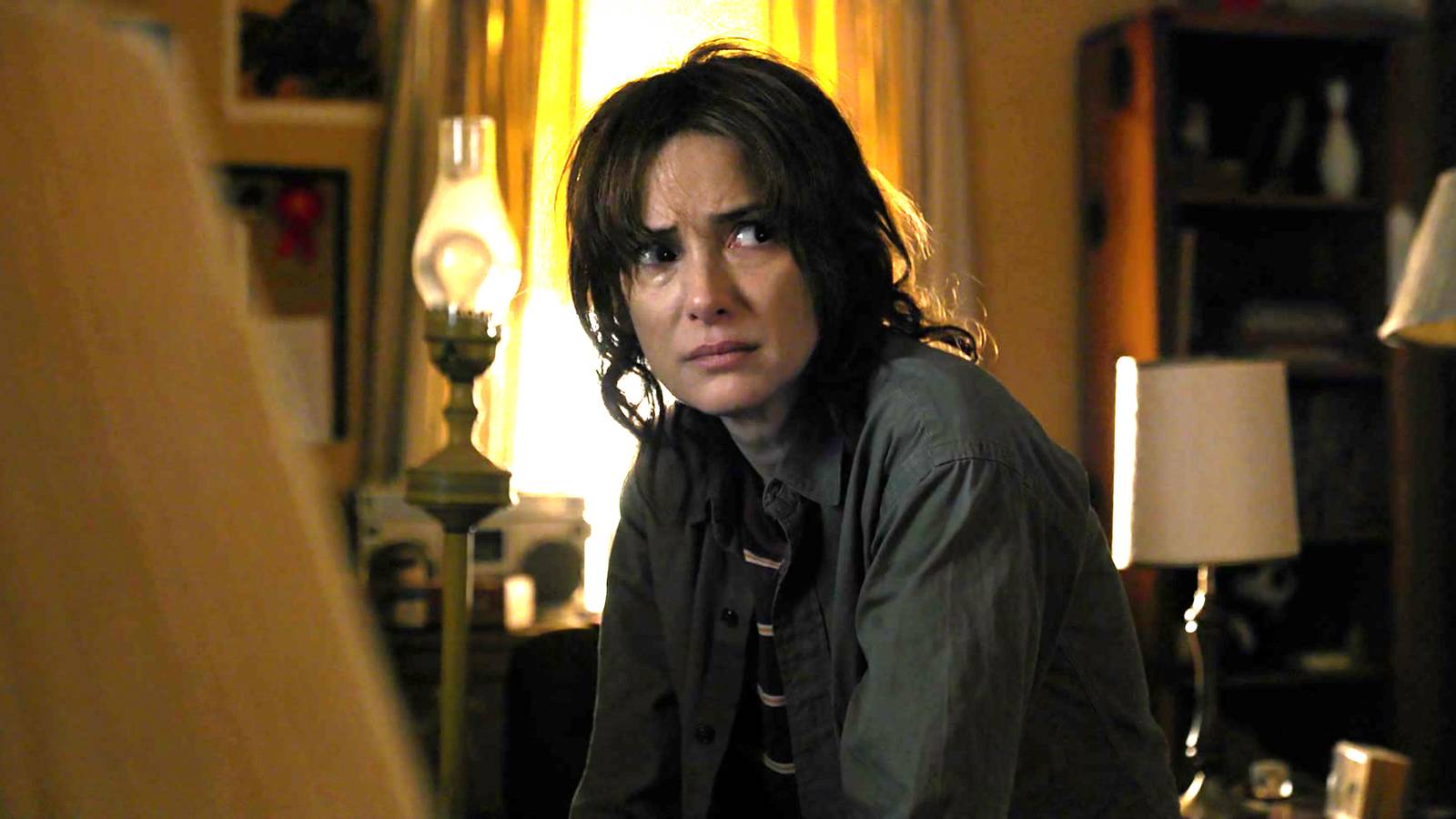 Winona Ryder as Joyce looking distraught in Will's messy room in Stranger Things season 1
