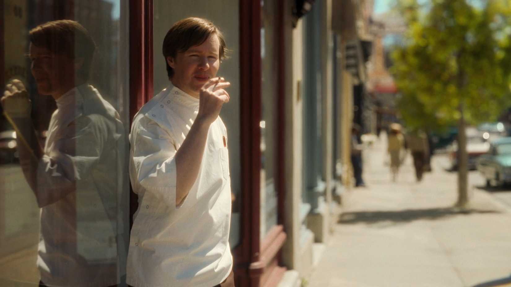 Jovem Keene fumando do lado de fora da farmácia em Welcome to Derry episódio 2