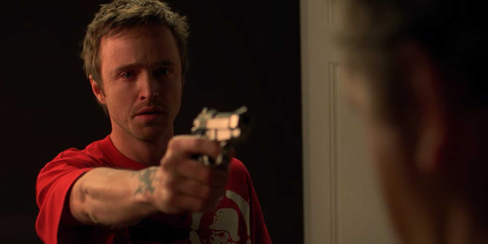 Aaron Paul como Jesse chorando enquanto aponta uma arma em Breaking Bad