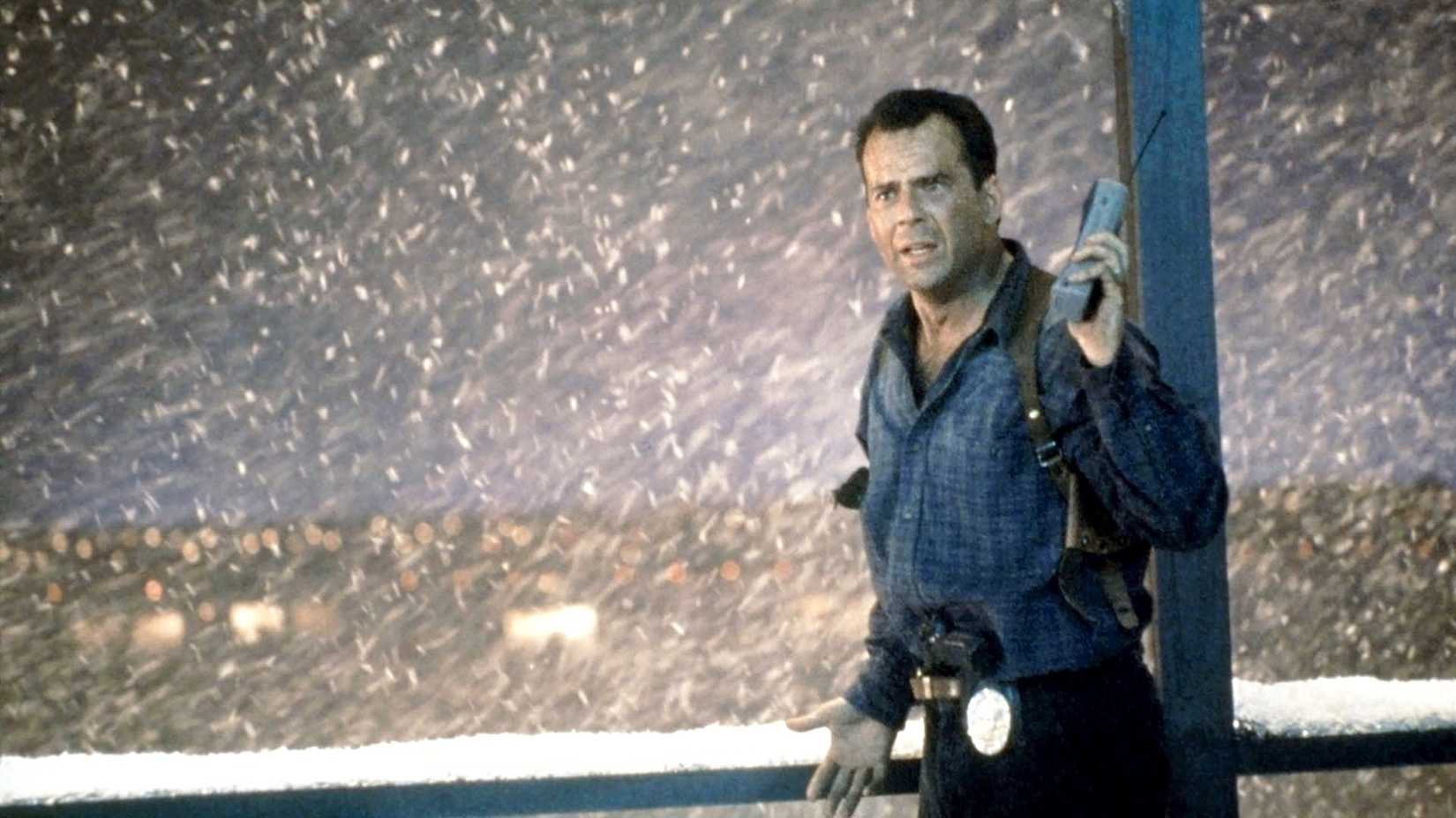 Брюс Уиллис рядом со снегом, держащий рацию в Die Hard 2