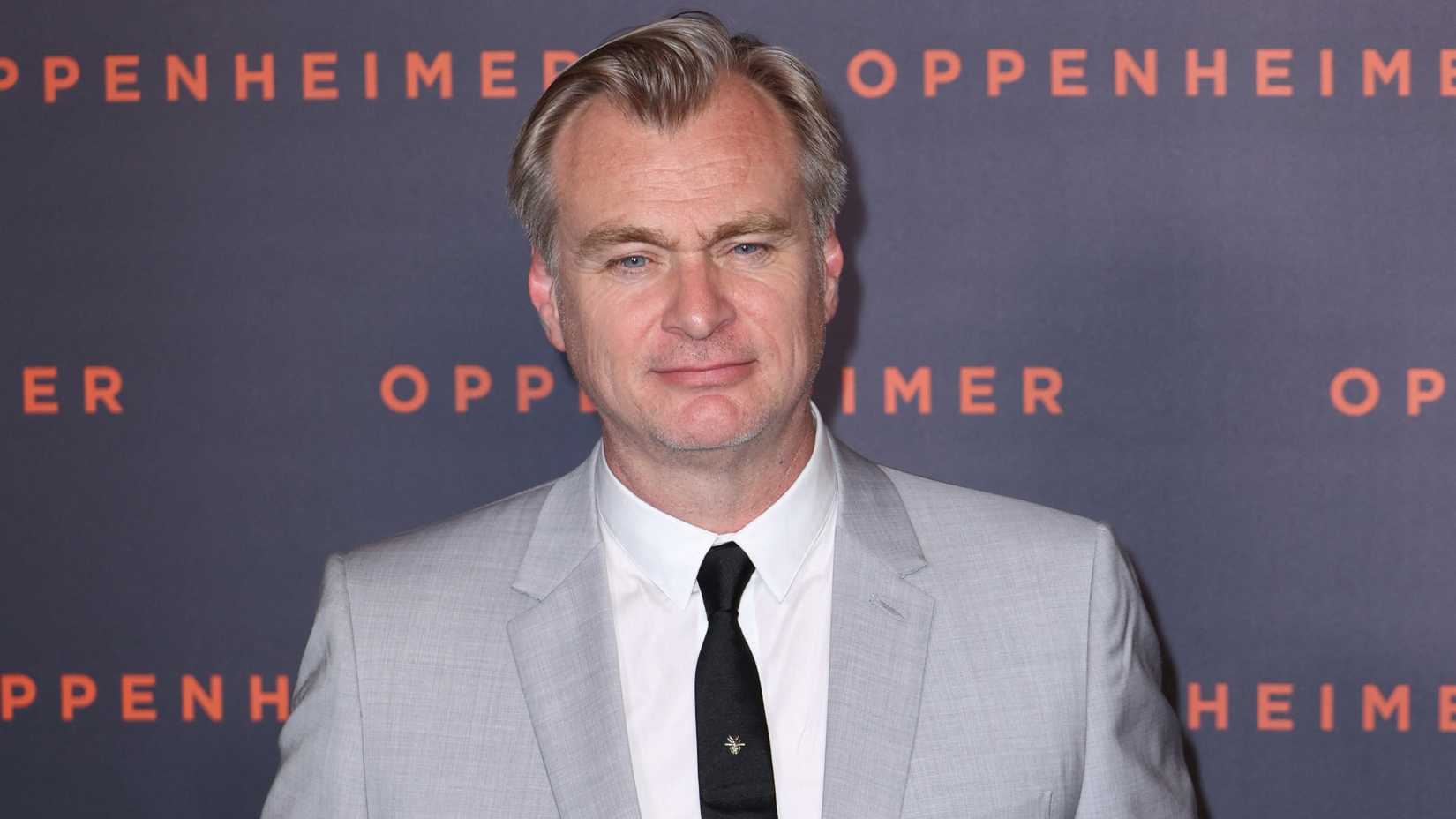 Christopher Nolan straight-faced while posing at a red carpet event