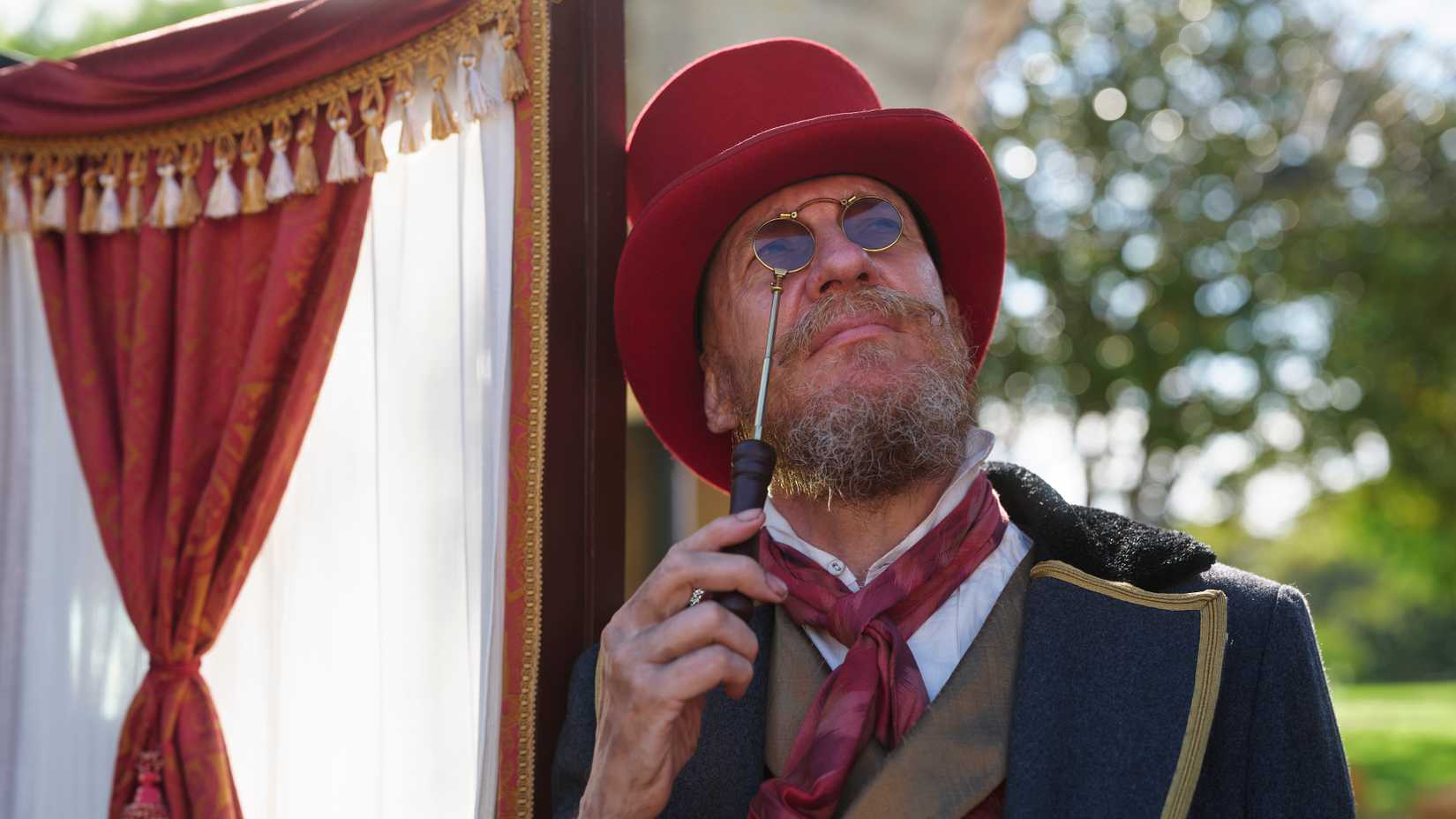 David Thewlis as Fagin wearing a read top hat and glasses in The Artful Dodger season 2