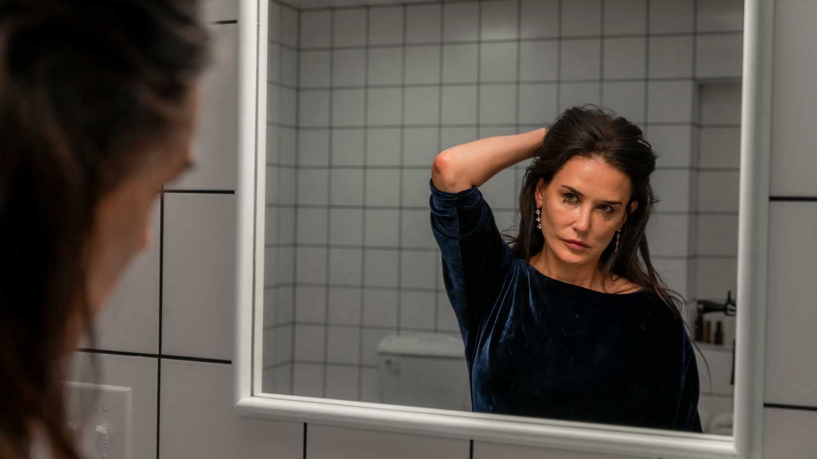 Demi Moore as Elisabeth Sparks looking at herself in the mirror in The Substance