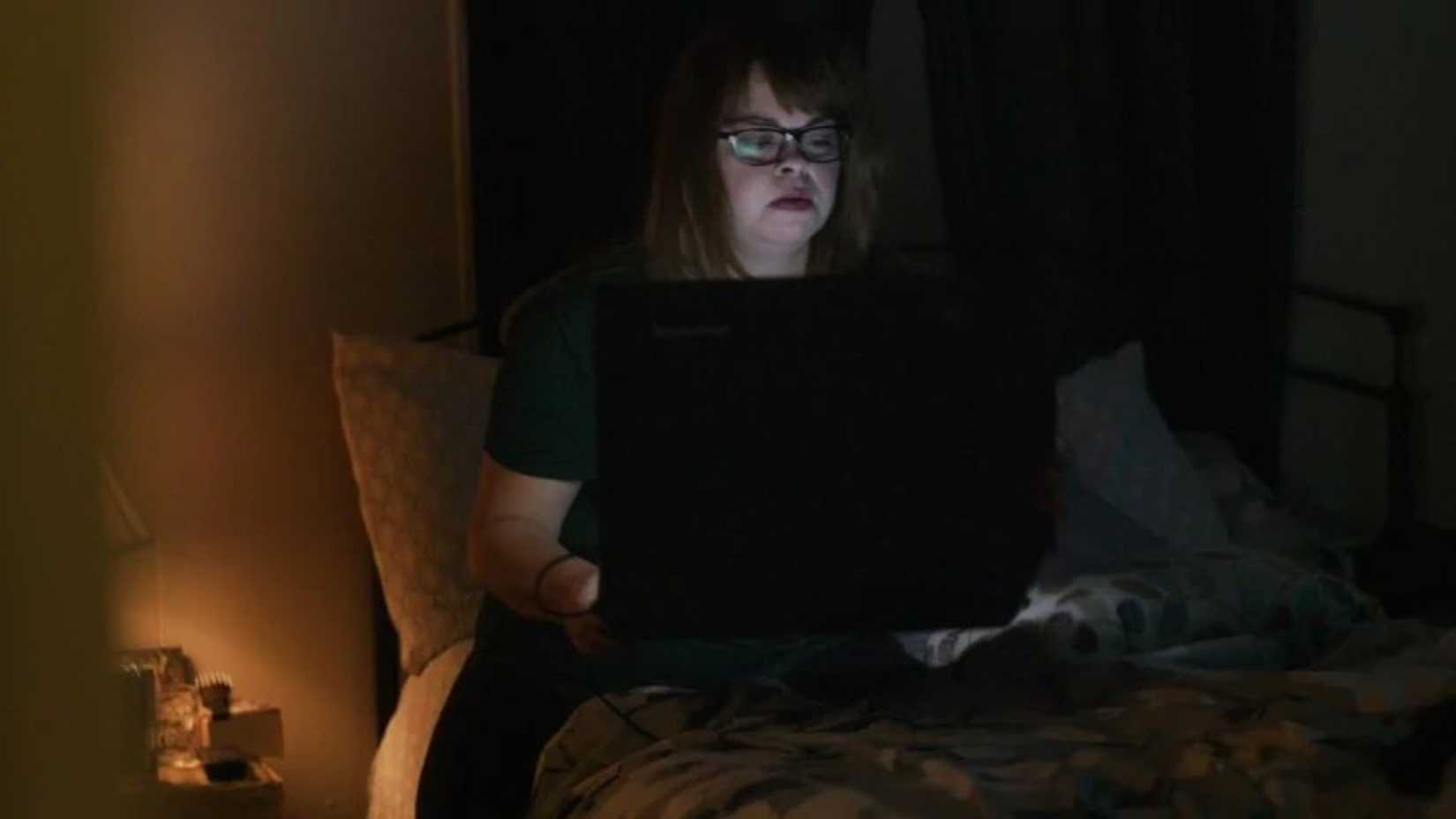 Uma mulher trabalha em seu laptop no escuro em Don't F**k With Cats.