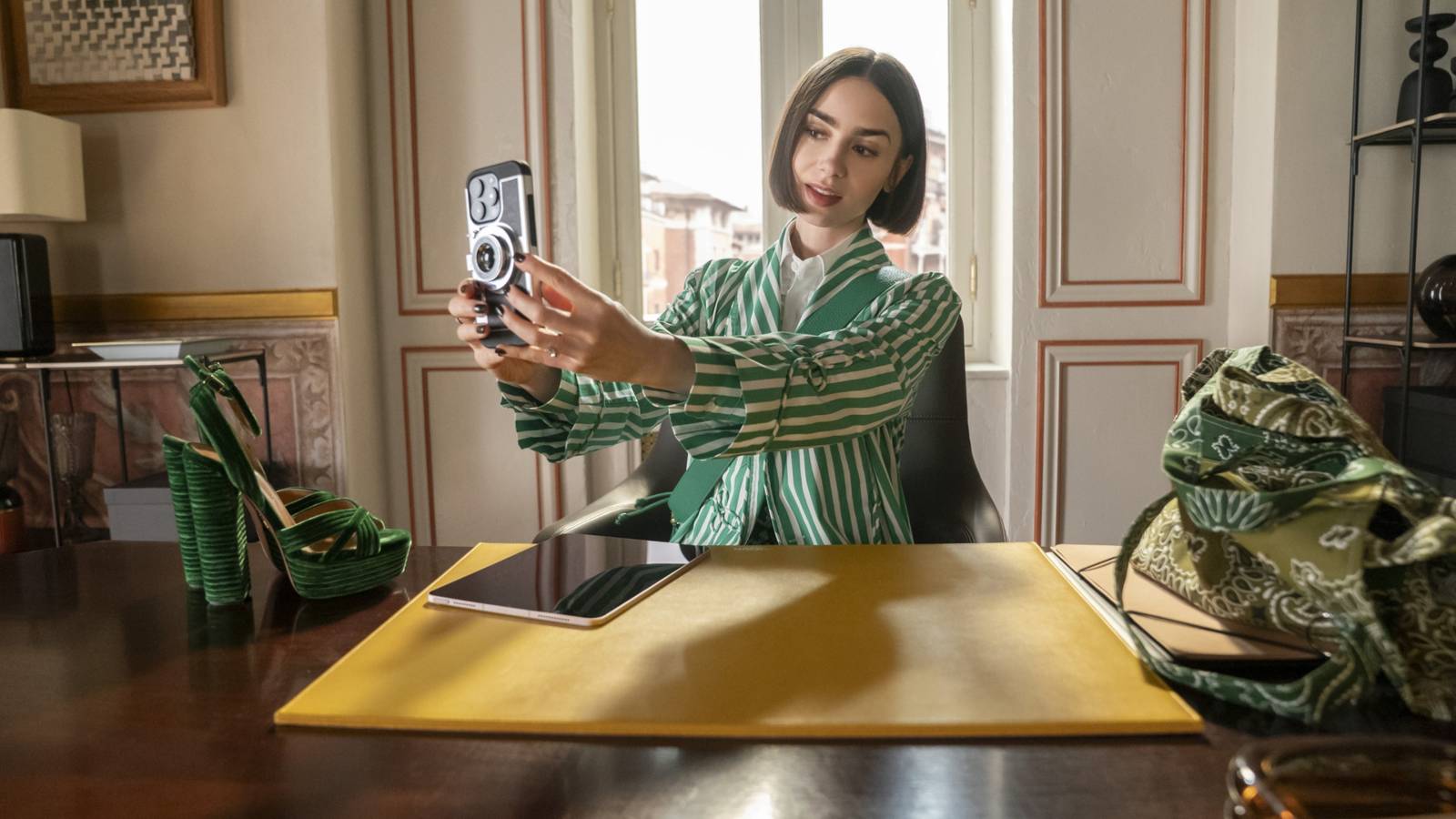 Emily Cooper (Lily Collins) taking a selfie at her desk in Rome in Emily in Paris season 5