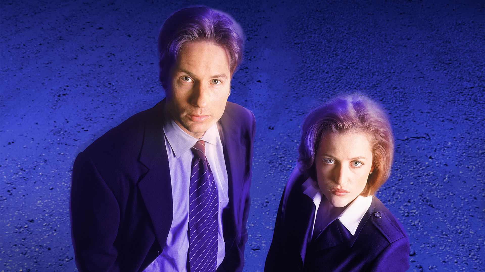 Gillian Anderson and David Duchovny standing together in a promo photo for The X-Files
