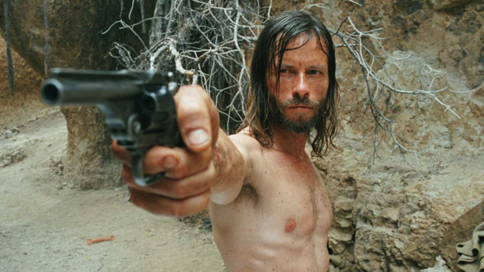 Guy Pearce como Charlie Burns com uma arma em The Proposition