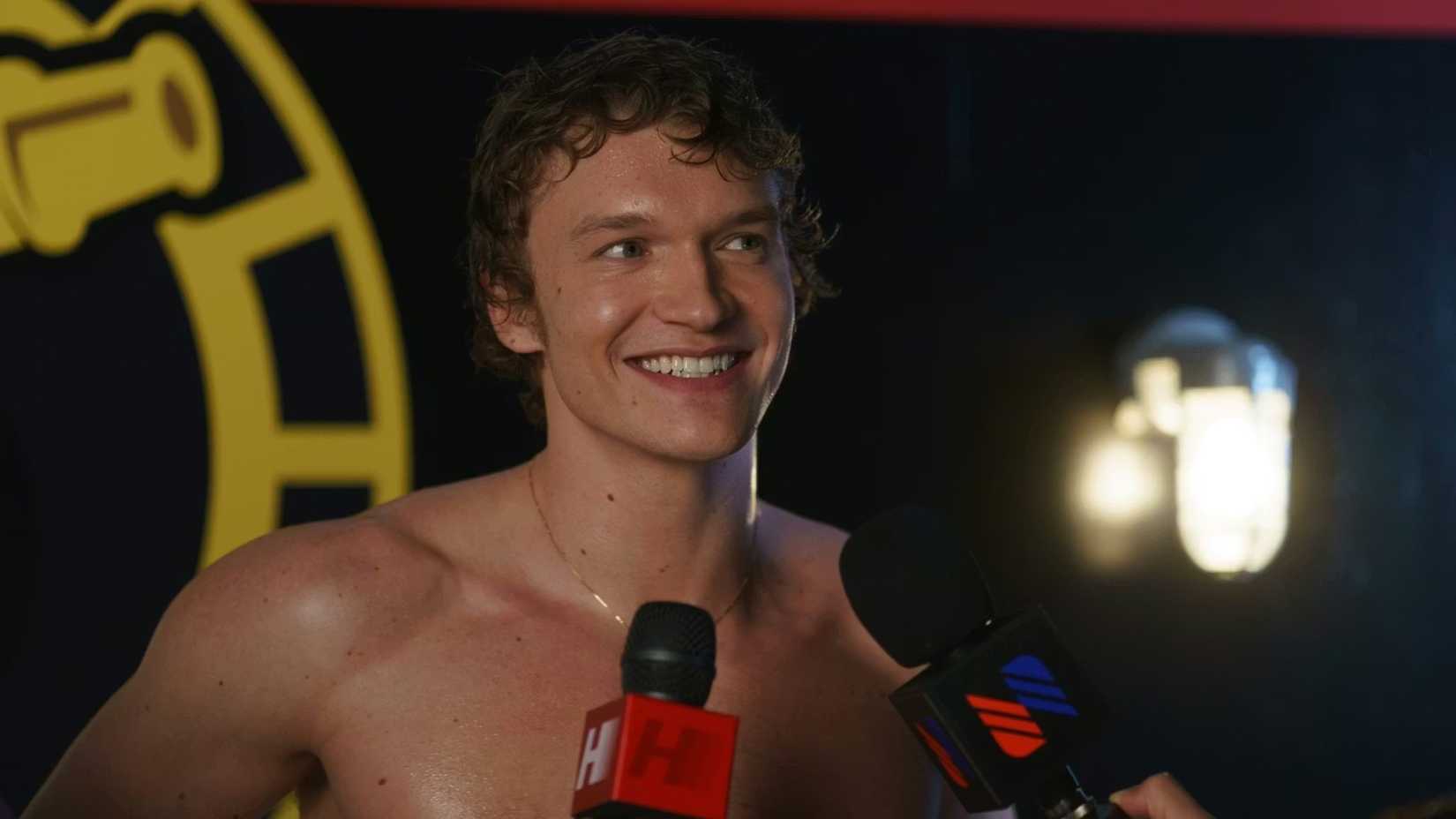 Connor Storrie smiling shirtless as Ilya Rozanov in Heated Rivalry.