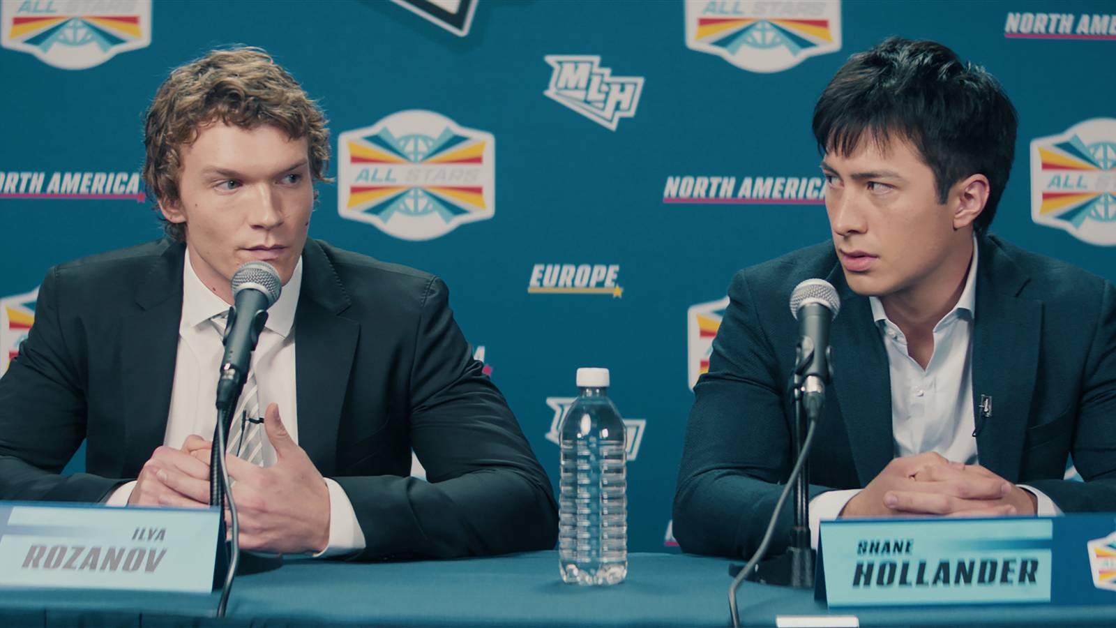 Ilya Rozanov (Connor Storrie) and Shane Hollander (Hudson Williams) at a press conference in Heated Rivalry.