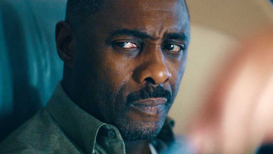 Idris Elba looking grim while sitting on a plane in Hijack season 1