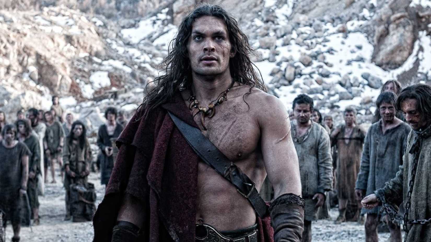 Jason Momoa as Conan the Barbaran standing and looking serious in Conan the Barbarian
