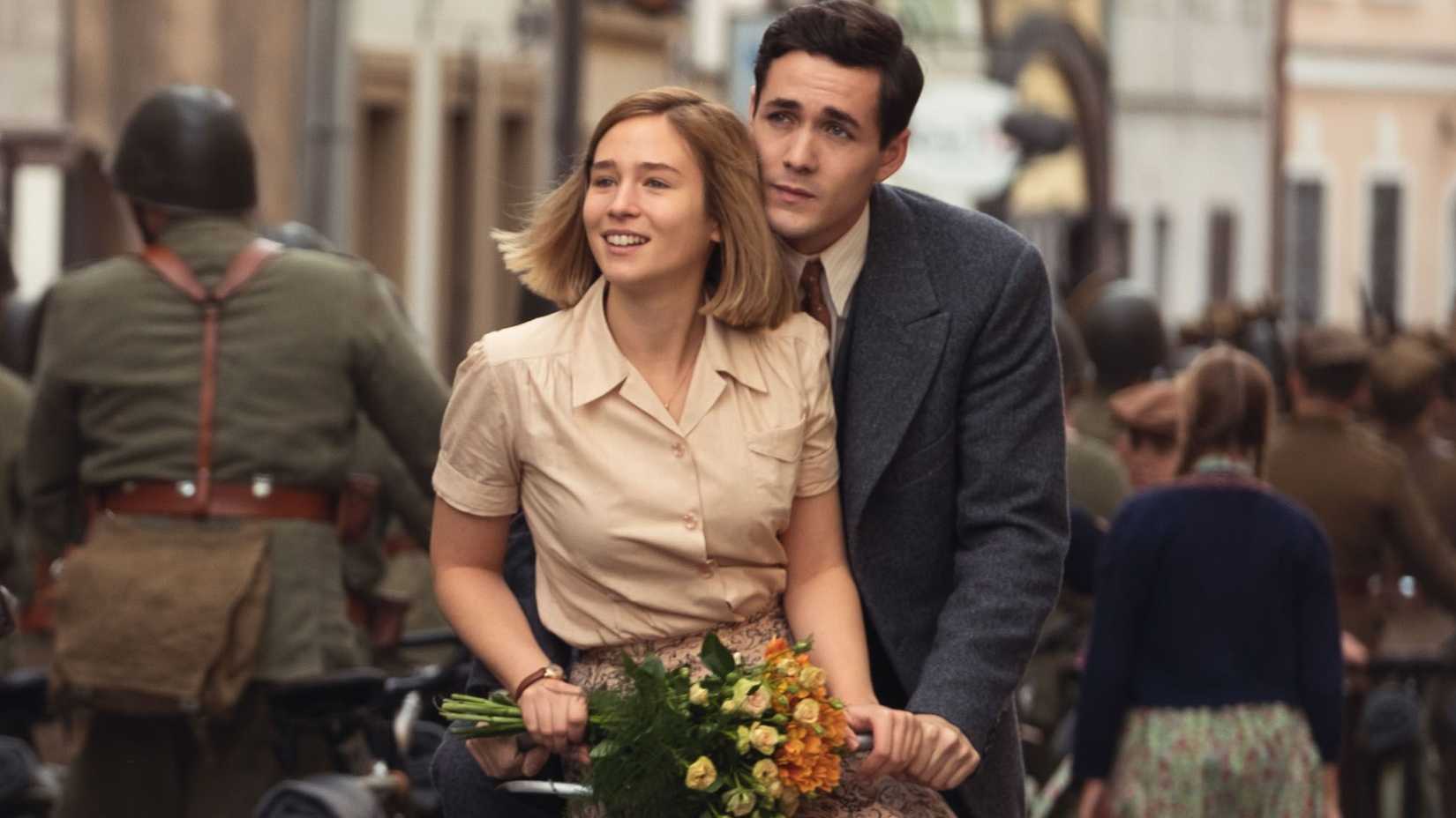 Kasia Tomaszeski (Zofia Wichłacz) and Harry Chase (Jonah Hauer-King) riding a bike together in World on Fire