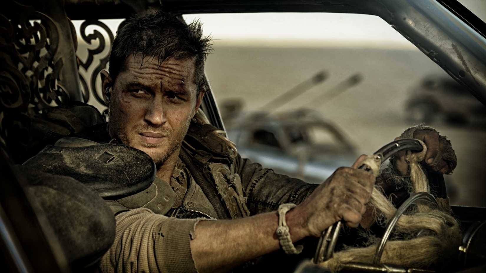Max olha por cima do ombro enquanto está sentado em um carro em Mad Max: Estrada da Fúria