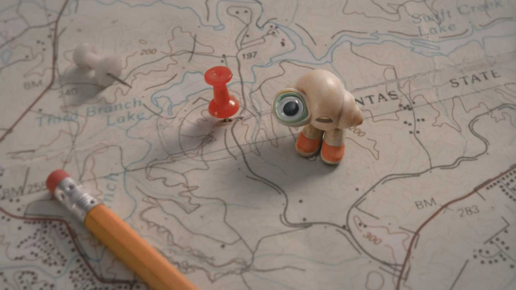 Marcel fica em um mapa olhando para cima em Marcel the Shell with Shoes On