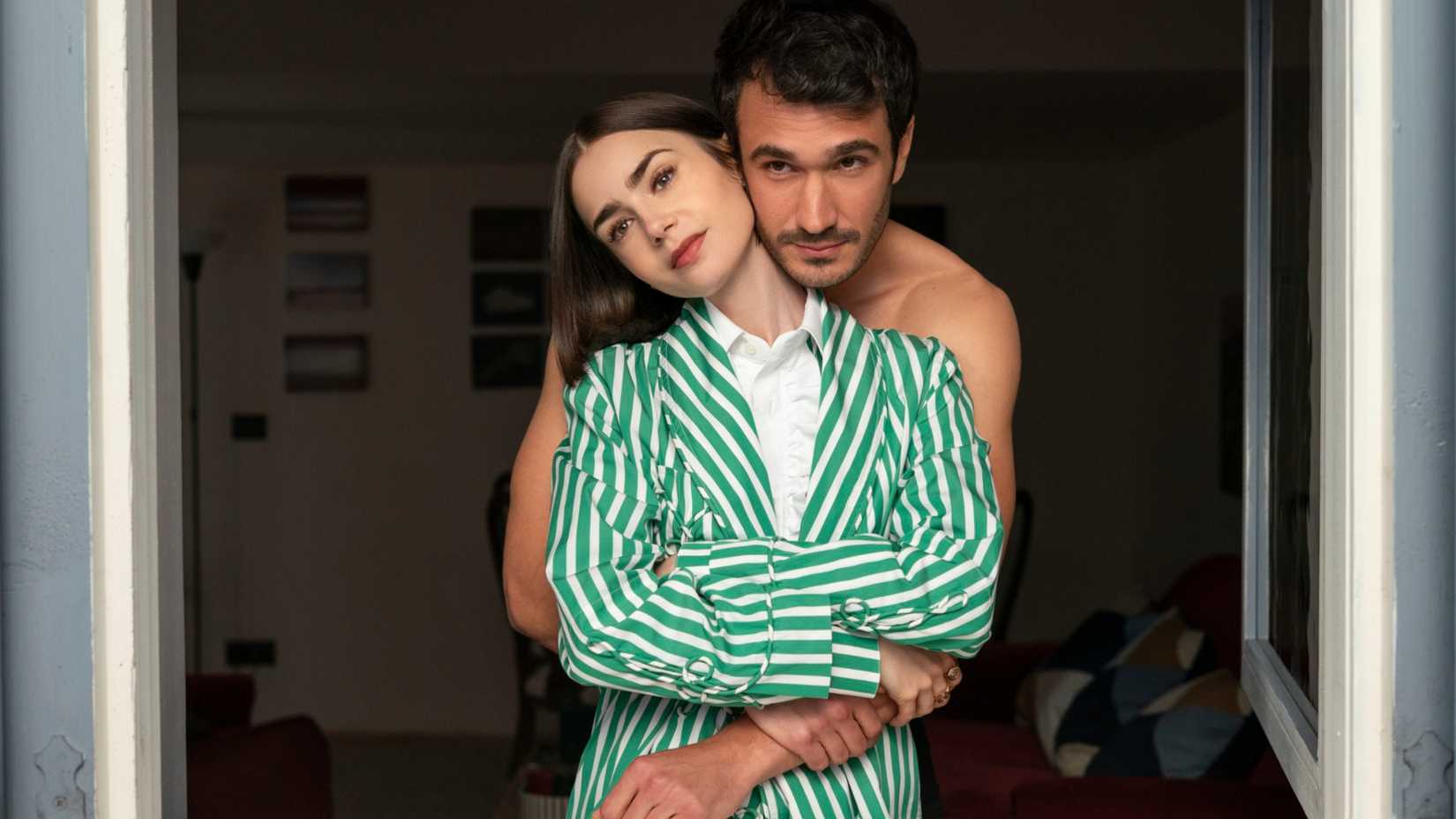 marcello with his arms around emily as the both gaze out a window in the emily in paris season 5 premier