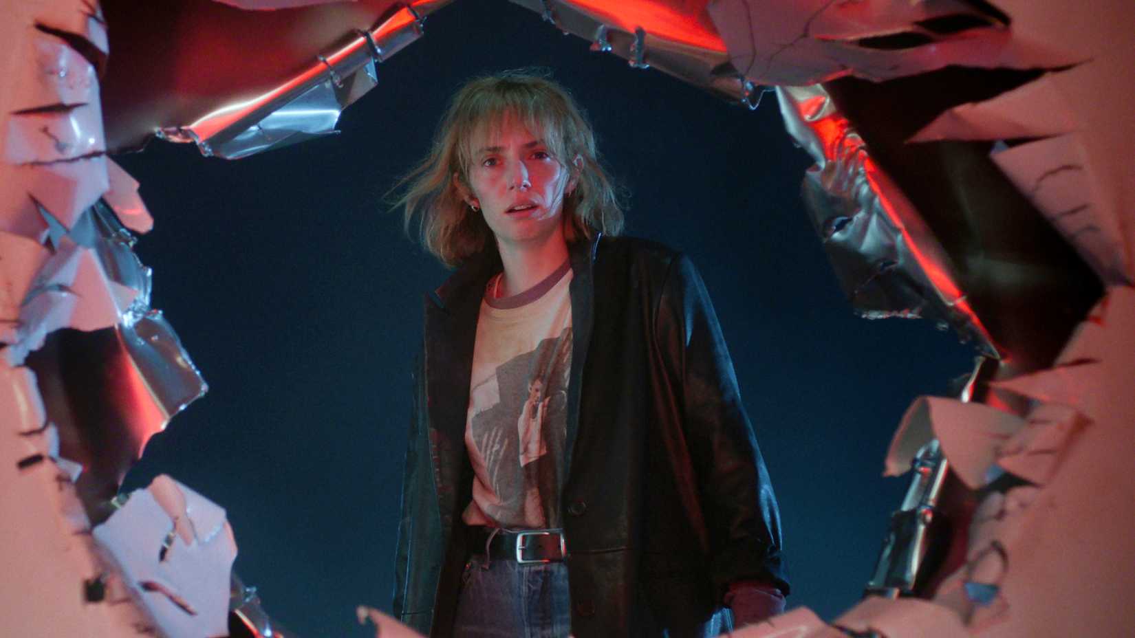 Maya Hawke as Robin looking through an Upside Down tear while confused in Stranger Things season 5