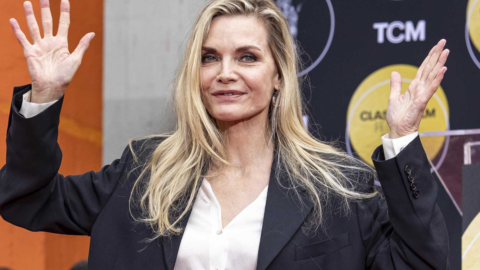 Michelle Pfeiffer holding out her hands at her Walk of Fame ceremony