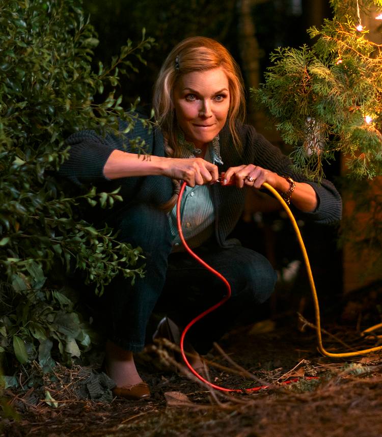 Michelle Pfeiffer's Claire looking mischievous while squatting to unplug Christmas trees in Oh. What. Fun.