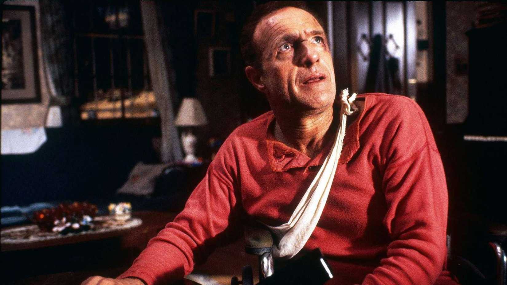 James Caan olhando para cima de sua cadeira de rodas em Misery