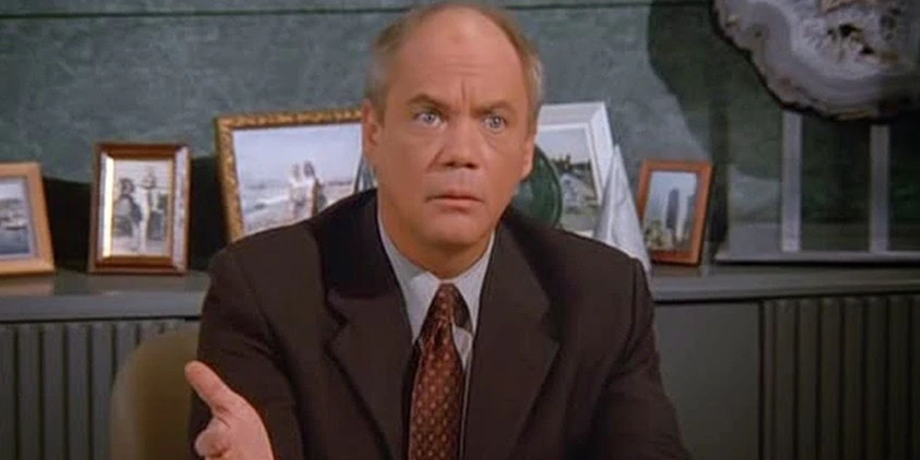 Mr Kruger seduto alla scrivania in Seinfeld