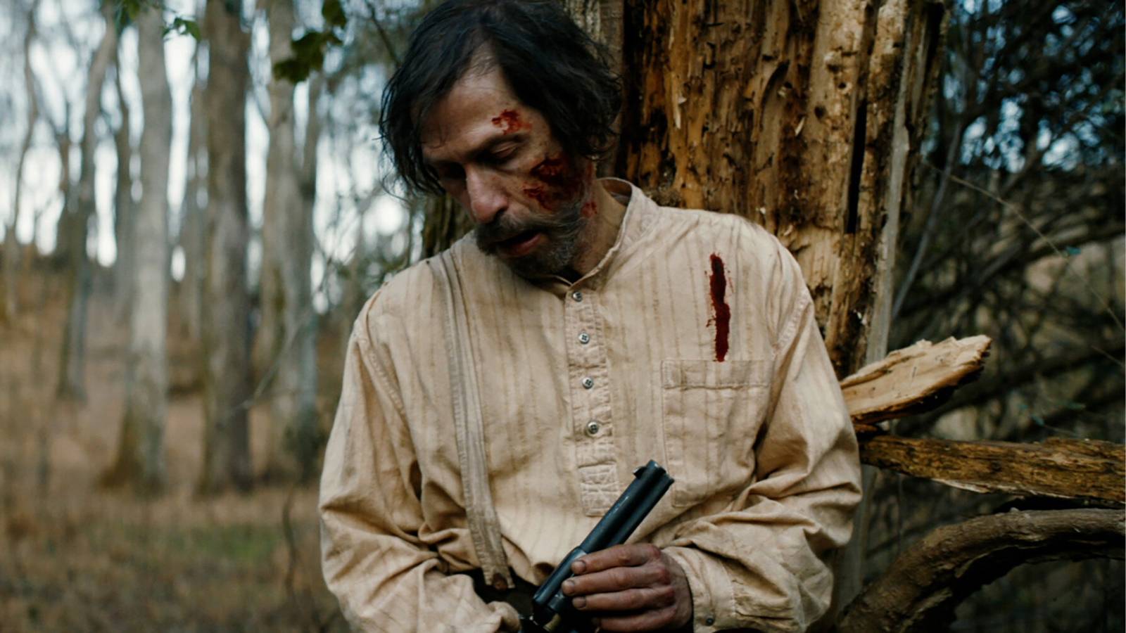 Old Henry holding gun and with blood