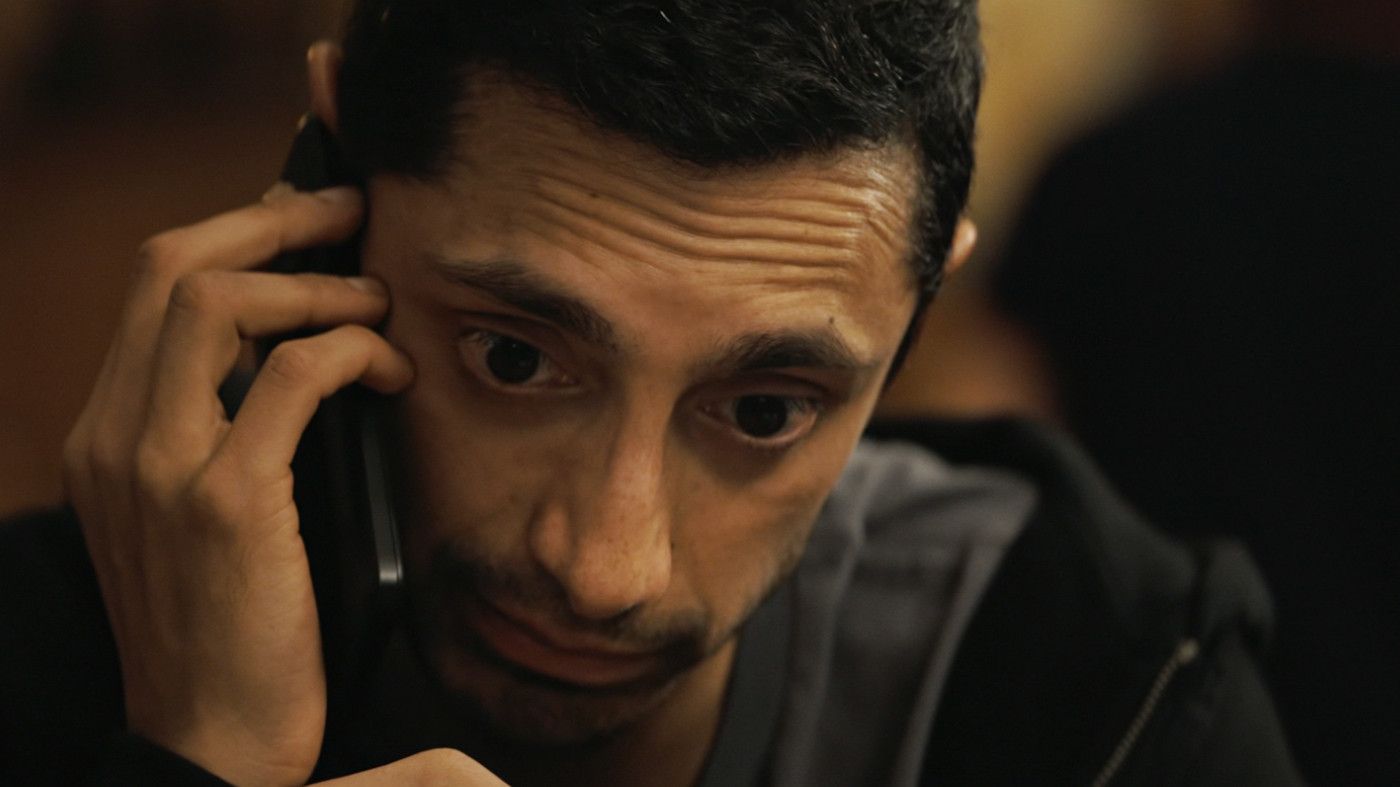 Riz Ahmed looks intense while talking on the phone in a scene from Relay