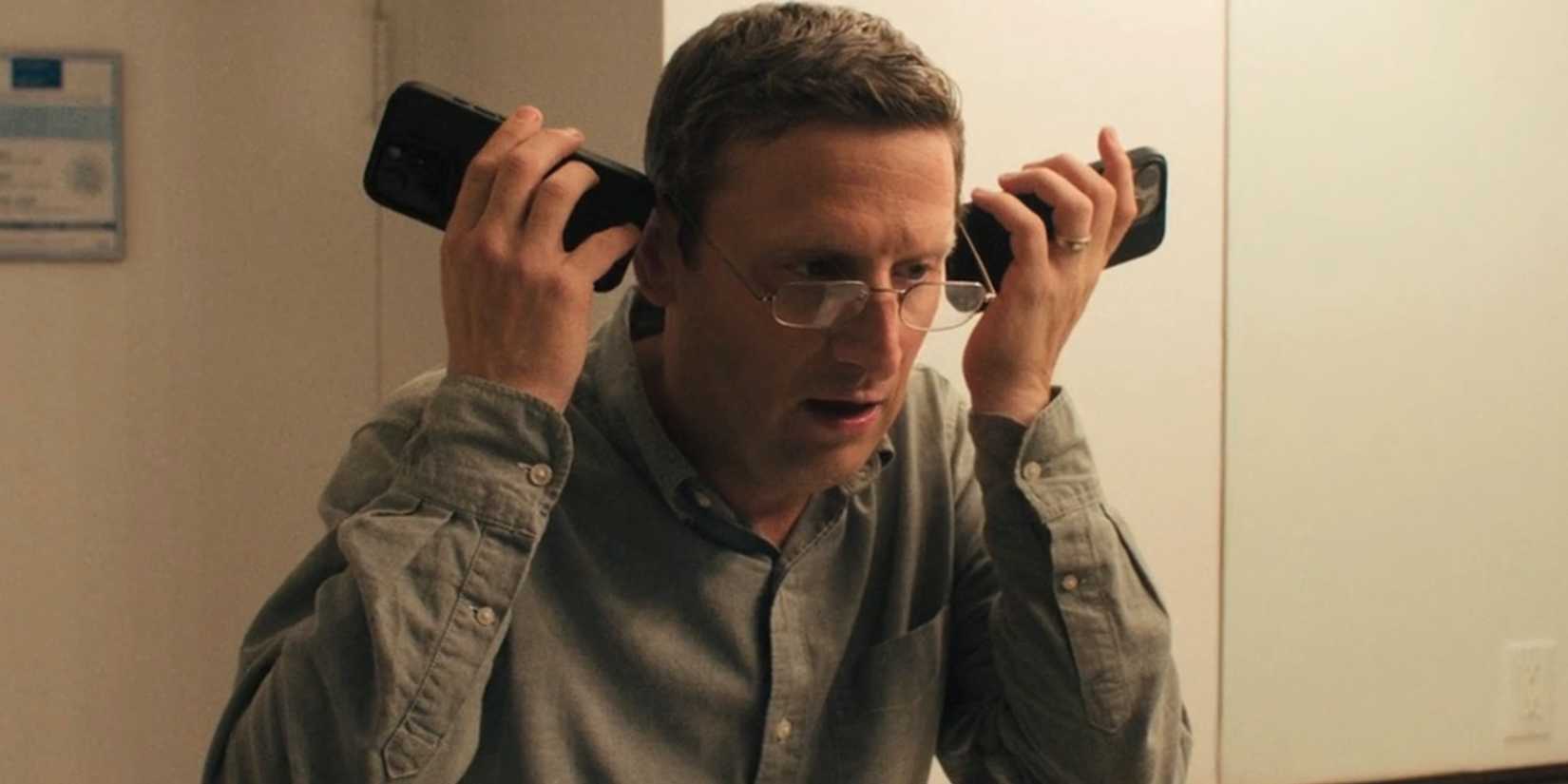 Ron ouvindo dois telefones em The Chair Company