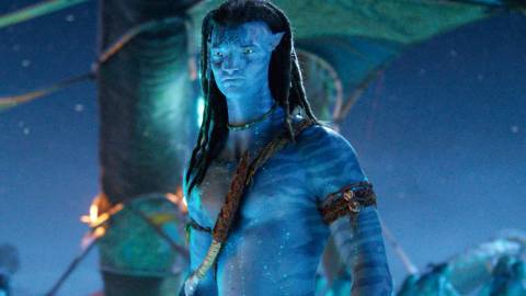 Sam Worthington as Jake standing in front of a tree in Avatar Fire and Ash