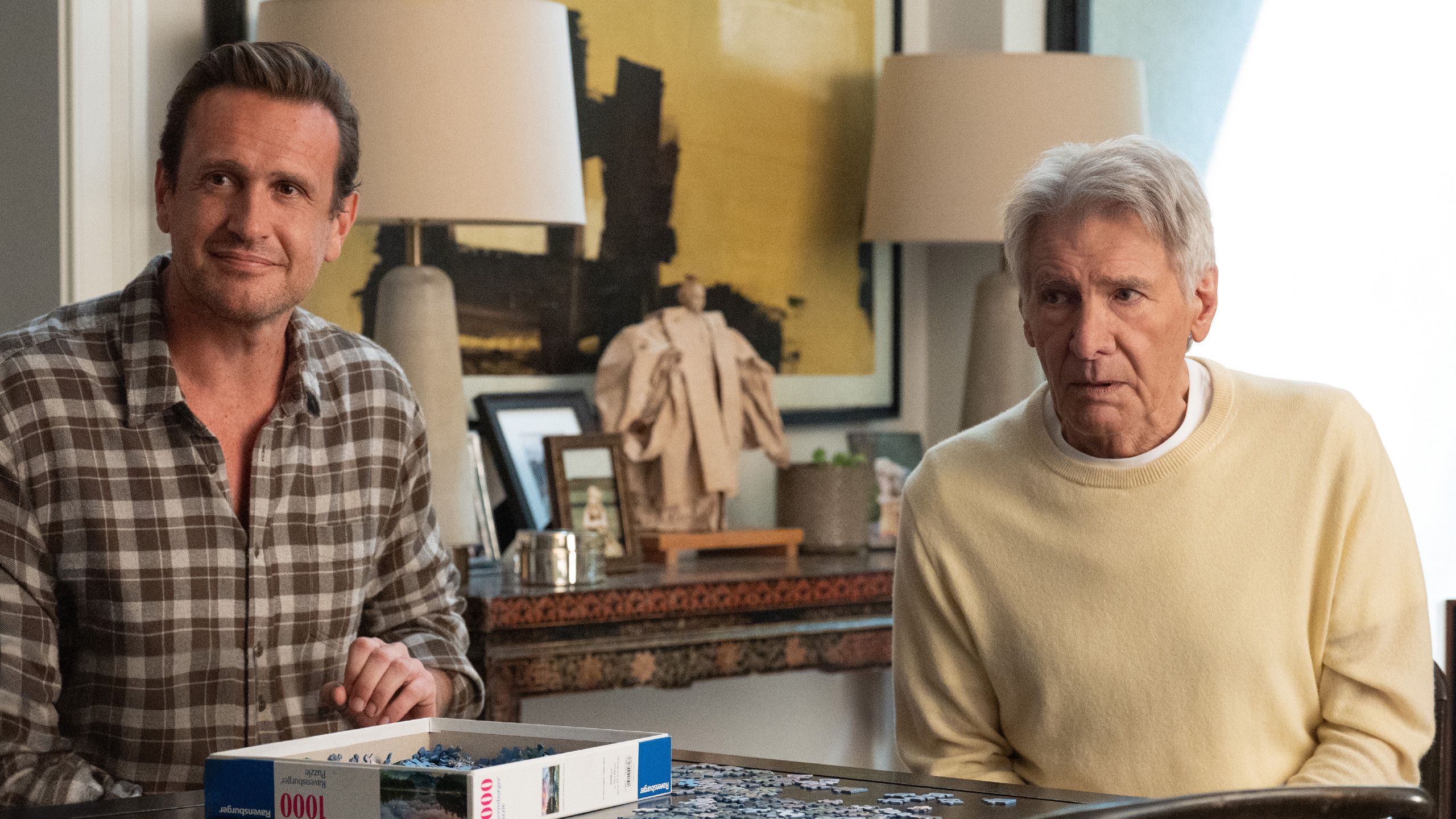 Shrinking still featuring Jason Segel and Harrison Ford sitting at a table with a puzzle.