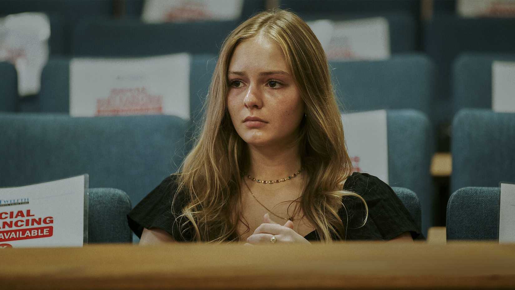 Uma jovem está com os olhos marejados em um tribunal.