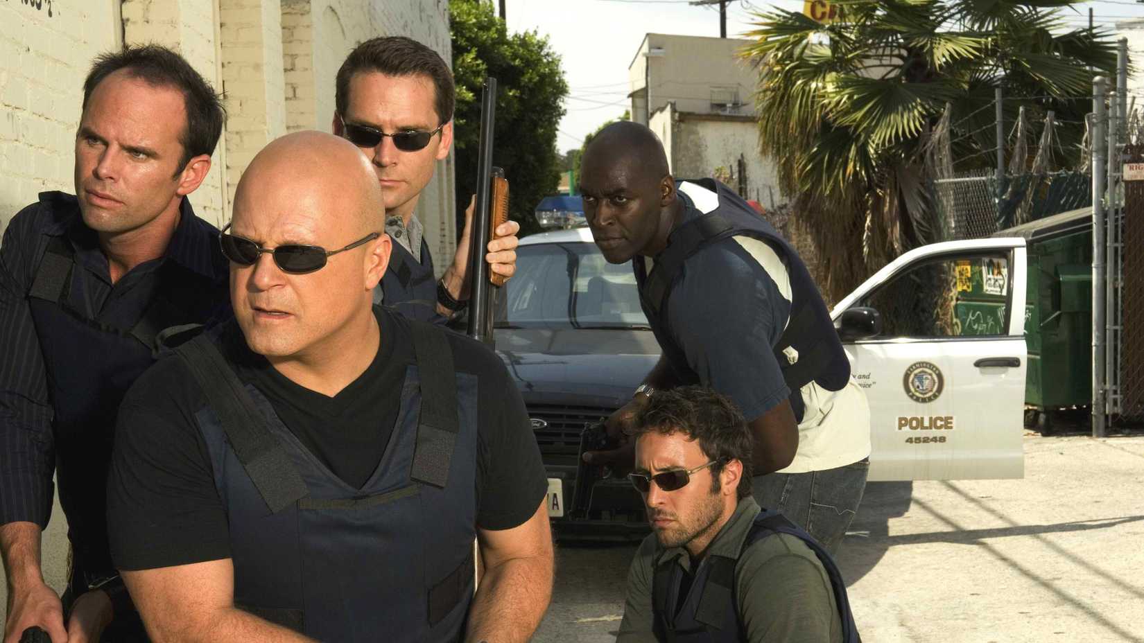 O elenco de The Shield, armado, do lado de fora e preparado para invadir um prédio