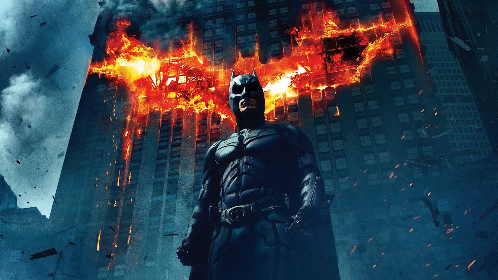 Batman & Superman Lead The Pack 7 Batman standing in front of a building with his logo on fire in The Dark Knight