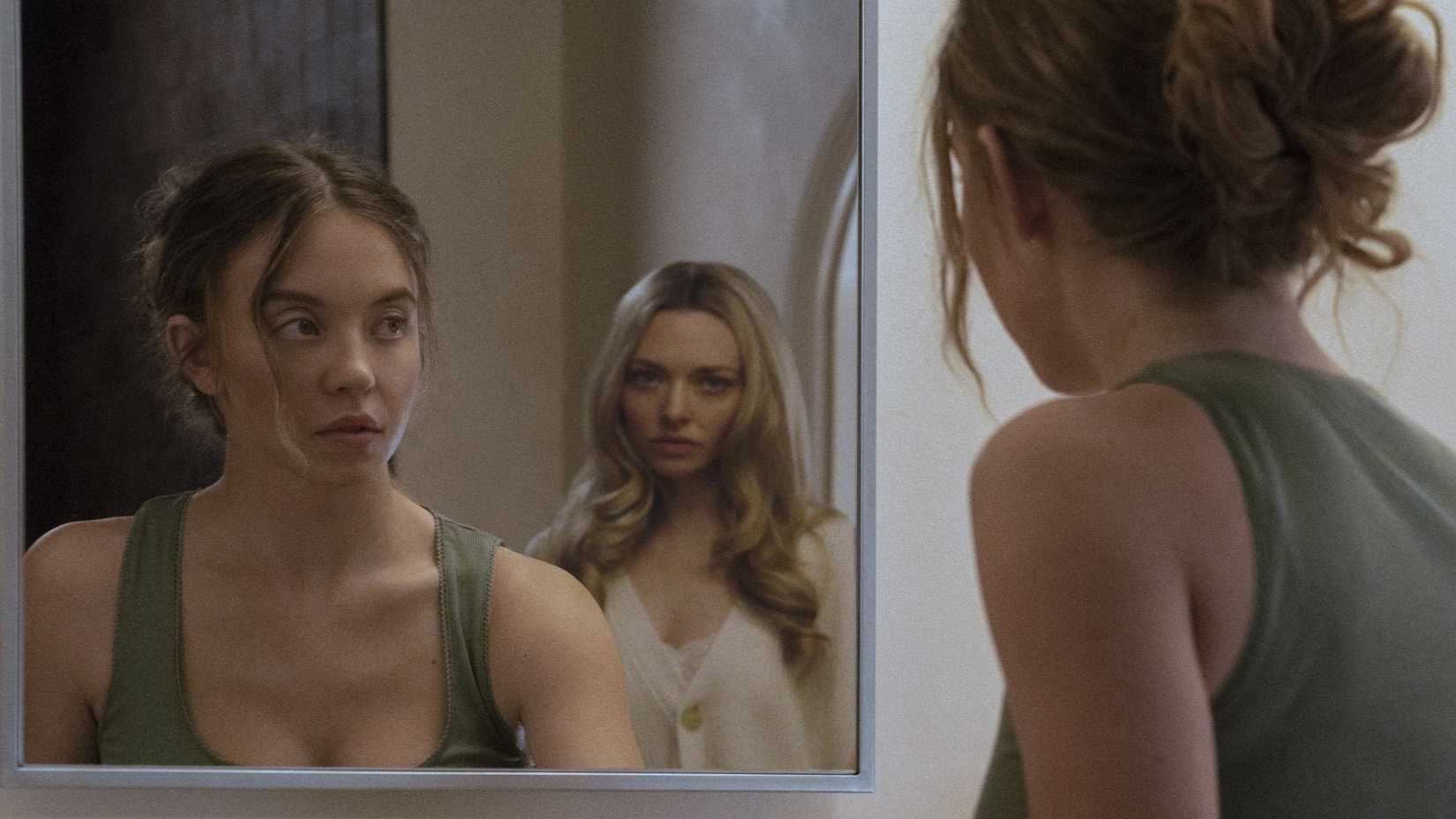 Sydney Sweeney as Millie Calloway looking at Amanda Seyfried as Nina Winchester in the mirror in The Housemaid