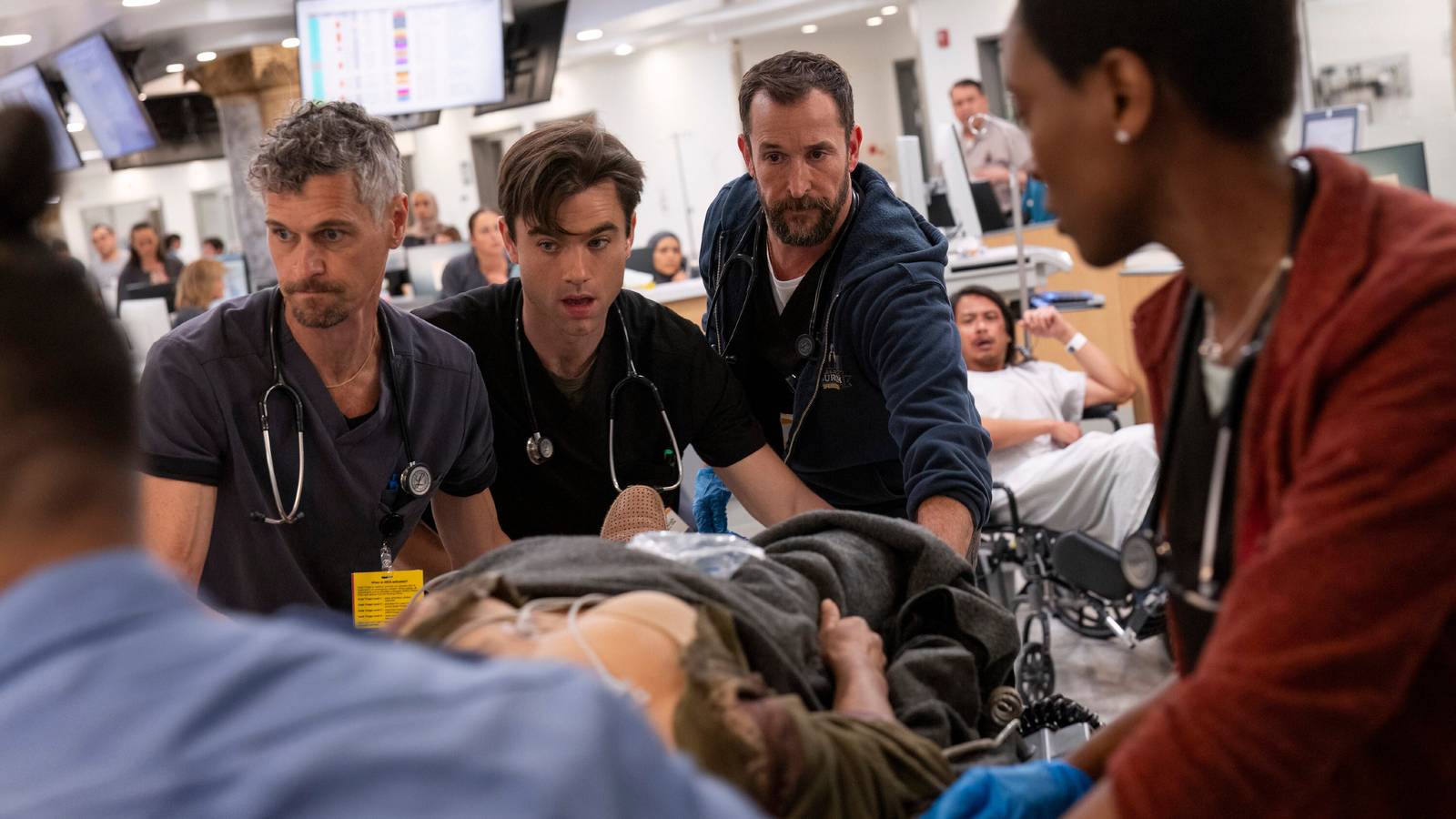 The Pitt's team including Dr. Robby, Dr. Langdon, and Dr. Collins wheeling a patient on a gurney.