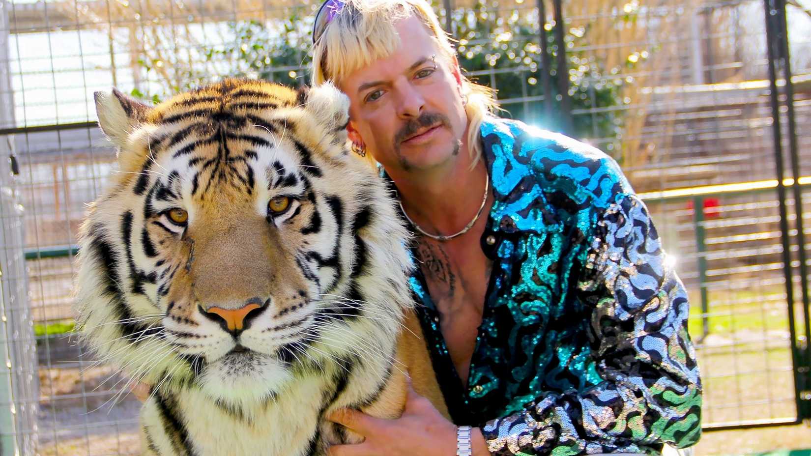 Joe Exotic posa ao lado de um tigre.