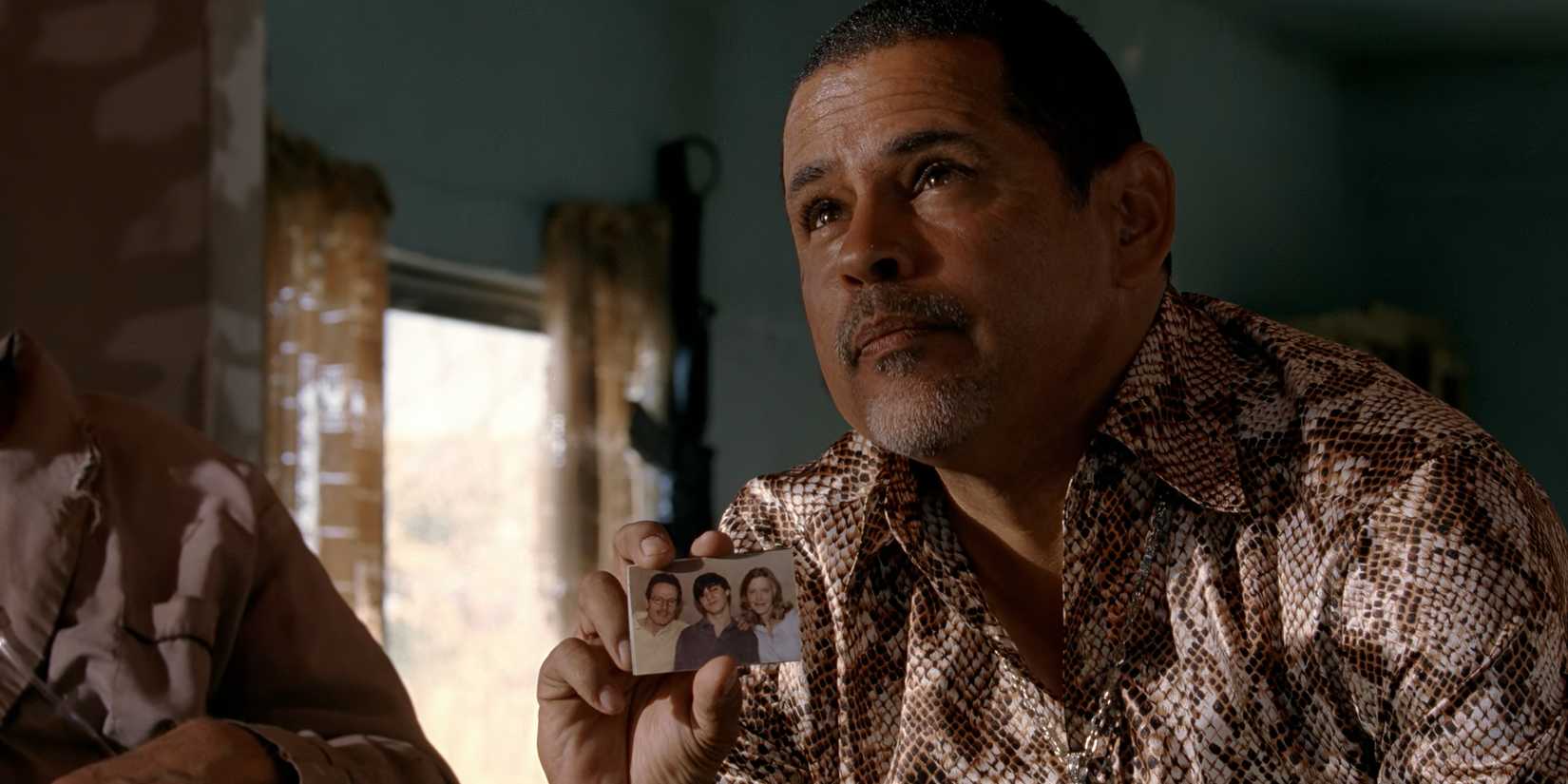 Tuco segurando uma foto da família de Walt e olhando para cima em Breaking Bad