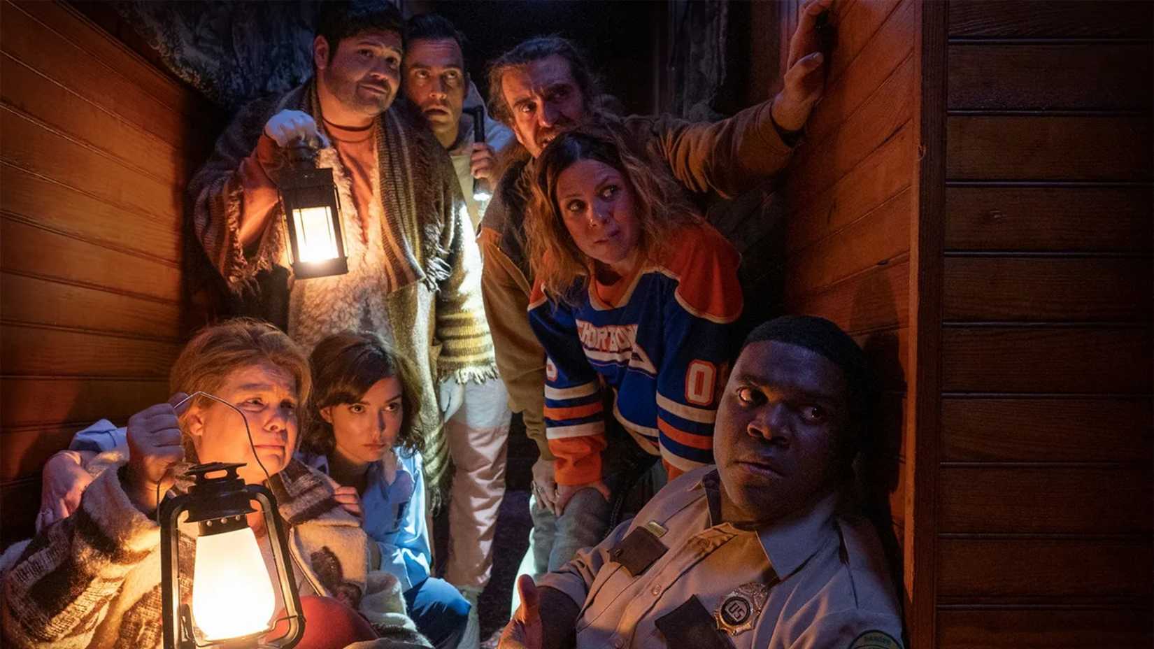 The cast huddles around a lantern in Werewolves Within