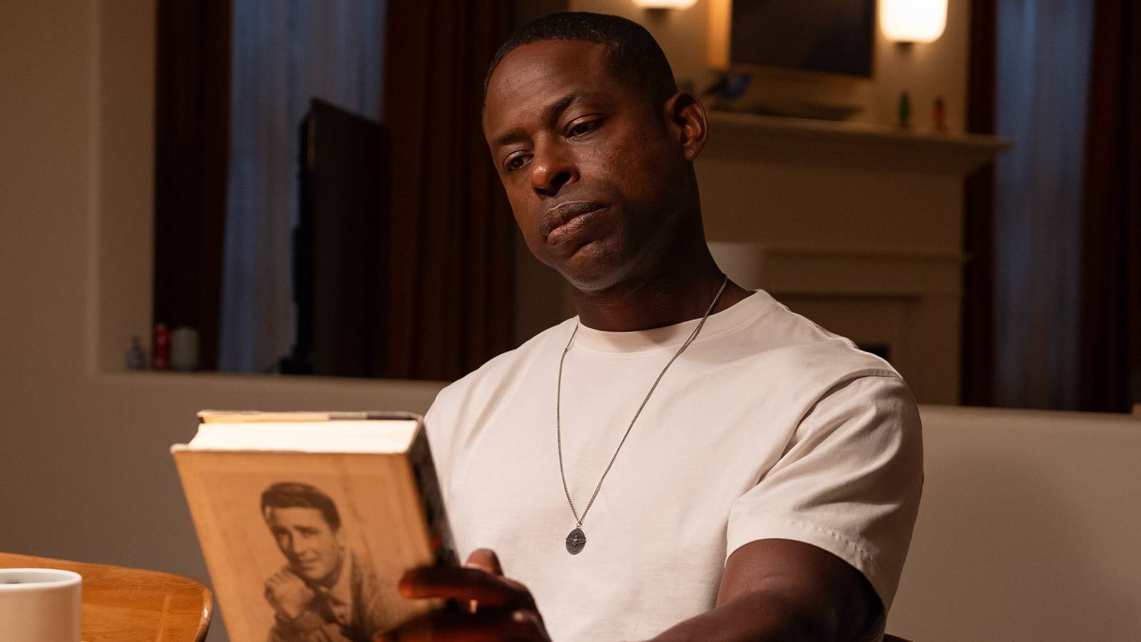 Sterling K. Brown as Xavier sitting in the kitchen while looking at a book in Paradise season 1