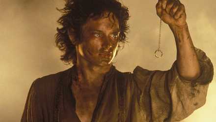 A dirty and exhausted Frodo holding the One Ring on a chain in front of him in The Lord of the Rings The Return of the King