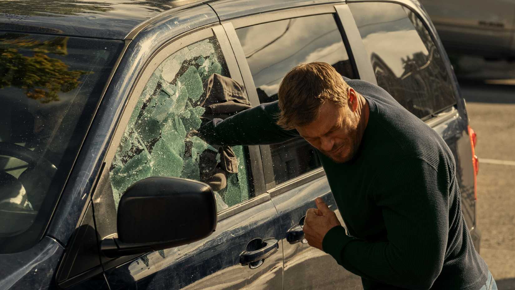 Alan Ritchson como Reacher quebrando janela de carro com soco